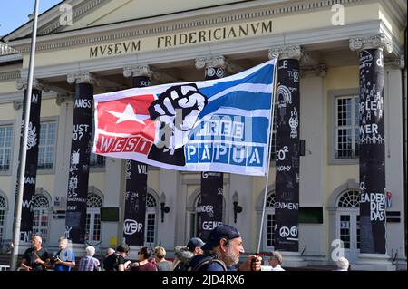 Kassel, Germania. 18th giugno 2022. 'Free West Papua' è scritto su una bandiera tenuta in alto da un uomo all'apertura di documenta quindici davanti al Fridericianum. Il documento quindici è stato aperto alla presenza del Presidente tedesco e dura fino al settembre 25. Credit: Uwe Zucchi/dpa/Alamy Live News Foto Stock