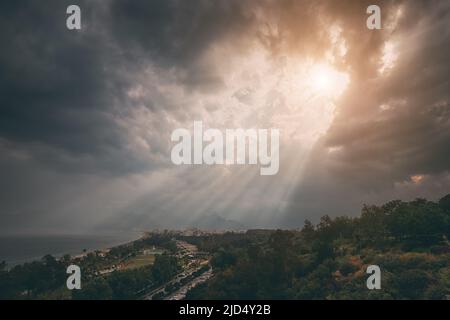 La maestosa e drammatica luce del sole attraversa le dense nuvole della spiaggia di Konyaalti ad Antalya, in Turchia. Sfondi delle destinazioni di viaggio Foto Stock