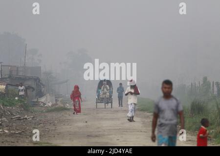 Dhaka, Bangladesh. 16th giugno 2022. Il treno trasporta passeggeri attraverso l'inquinamento e le donne e gli uomini e i bambini sono vulnerabili condizione un'area inquinata dall'aria quando il fumo sale da un laminatoio a Dhaka, Bangladesh. Credit: Abaca Press/Alamy Live News Foto Stock