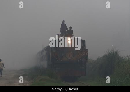 Dhaka, Bangladesh. 16th giugno 2022. Il treno trasporta passeggeri attraverso l'inquinamento e le donne e gli uomini e i bambini sono vulnerabili condizione un'area inquinata dall'aria quando il fumo sale da un laminatoio a Dhaka, Bangladesh. Credit: Abaca Press/Alamy Live News Foto Stock