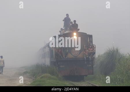 Dhaka, Bangladesh. 16th giugno 2022. Il treno trasporta passeggeri attraverso l'inquinamento e le donne e gli uomini e i bambini sono vulnerabili condizione un'area inquinata dall'aria quando il fumo sale da un laminatoio a Dhaka, Bangladesh. Credit: Abaca Press/Alamy Live News Foto Stock