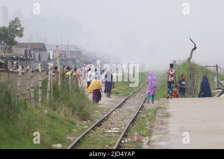 Dhaka, Bangladesh. 16th giugno 2022. Il treno trasporta passeggeri attraverso l'inquinamento e le donne e gli uomini e i bambini sono vulnerabili condizione un'area inquinata dall'aria quando il fumo sale da un laminatoio a Dhaka, Bangladesh. Credit: Abaca Press/Alamy Live News Foto Stock