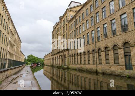 Vista esterna di Salts Mill e del canale Leeds & Liverpool, un ex mulino tessile, ora un centro di negozi d'arte a Saltaire, Bradford, West Yorkshire, Regno Unito. Foto Stock