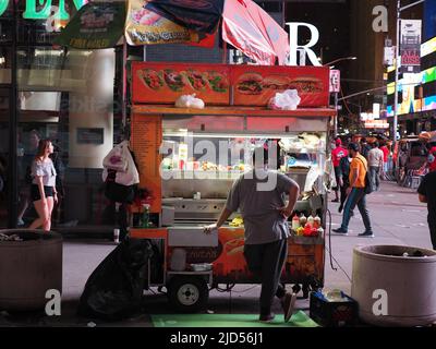 Un venditore che si trova dietro la bancarella di cibo vicino a Times Square. Foto Stock