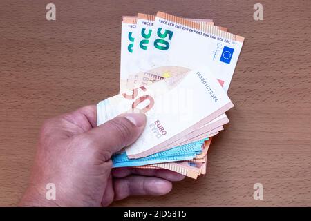 La mano contiene un mazzo di banconote da 20 e 50 euro sul tavolo Foto Stock