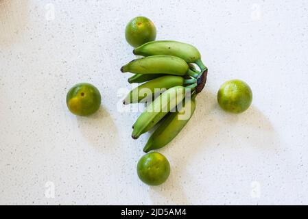 Quattro arance e un mazzo di banane verdi al centro su sfondo bianco. Salvador, Bahia, Brasile. Foto Stock