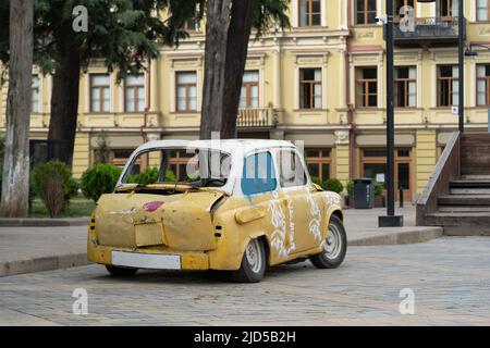 Guasto, vecchio parcheggio auto retro giallo bianco sul marciapiede in città con casa e alberi sullo sfondo. Foto Stock