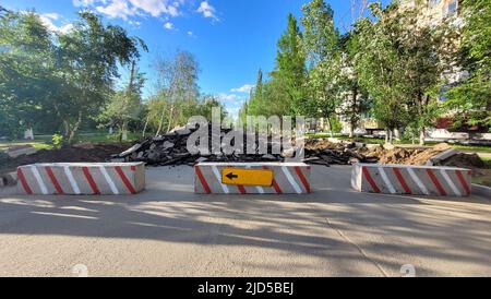 La strada è bloccata con blocchi di cemento a causa di riparazioni con un segno di deviazione sulla sinistra. Foto Stock