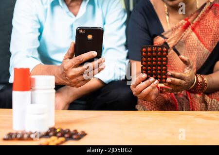 primo piano della vecchia coppia anziana che ordina medicinali sul telefono cellulare da casa - concetto di assistenza sanitaria, tecnologia e e-commerce Foto Stock