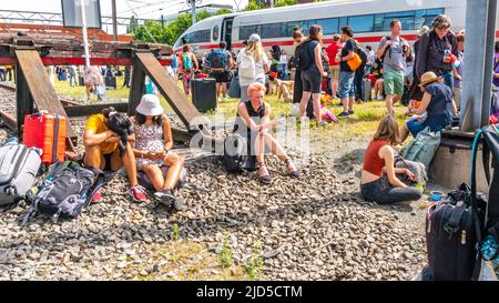 Hertogenbosch, Paesi Bassi. 18 Giu 2022. Passeggeri in attesa di sostituire il trasporto, seduti o in piedi al sole caldo tra le rotaie, accanto al treno internazionale rotto (ICE 153) che è venuto a fermarsi appena dopo la stazione di NS 's Hertogenbosch. Credit: Steppeland/Alamy Live News. Foto Stock