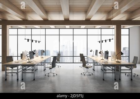 Vista frontale su eleganti file di spazio da lavoro con computer moderni su pavimento in cemento in uno spazioso ufficio con soffitto in legno e vista della città da enorme Foto Stock