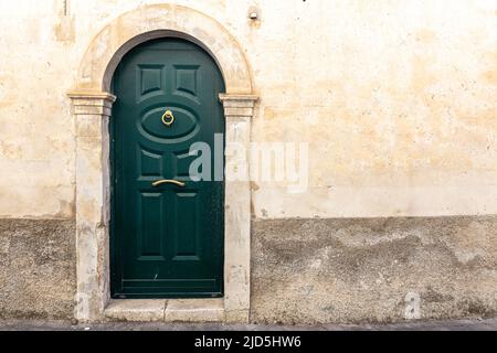 Porta verde con battente d'oro di una tipica casa siciliana Foto Stock