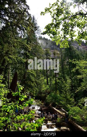 SQUAMISH, BC, CANADA, 02 GIUGNO 2019: Persone che riposano e si siedono su pietre ai piedi di Shannon Falls, Squamish, British Columbia Foto Stock