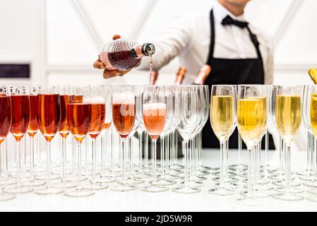 Il barista versa champagne in bicchieri. Bicchieri di champagne al bar. Un sacco di bevande alcoliche. Foto Stock