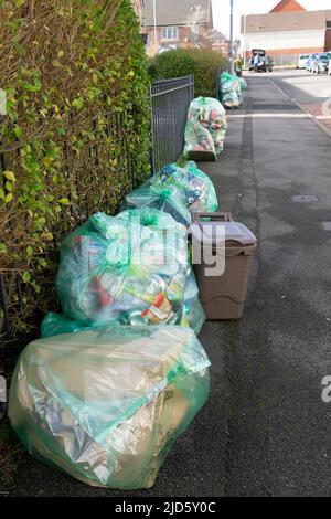 Fila di verde trasparente riciclaggio sacchi di rifiuti cor collezione lungo una strada di nuove case di costruzione a Cardiff Galles UK KATHY DEWITT Foto Stock