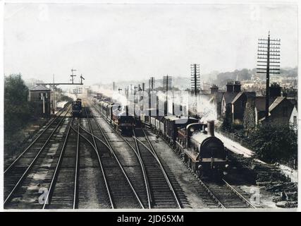 Un treno merci attende su una pista per far passare il treno passeggeri, mentre un terzo treno si avvicina attraverso la stazione di Redhill, Surrey. Versione colorata di : 10003799 Data: 1909 Foto Stock