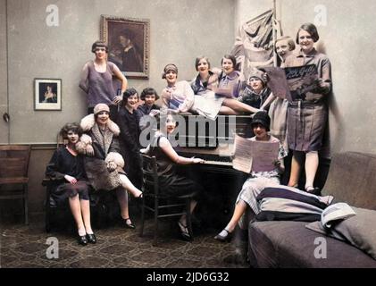 Piuttosto un equipaggio mottley di giovani donne vivaci riuniti intorno ad un pianoforte in un ostello per ragazze, Parigi, Francia. Versione colorata di : 10168254 Data: Fine 1920s Foto Stock