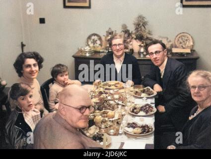 Famiglia estesa che mangia la cena di Natale. Tre generazioni festeggiano con la turchia e tutte le guarnizioni che il razionamento permetterebbe. Il giovane ragazzo (davanti a sinistra) indossa la tuta Martian Space che ha ricevuto per il suo regalo di Natale. Versione colorata di: 10794432 Data: Inizio 1950s Foto Stock