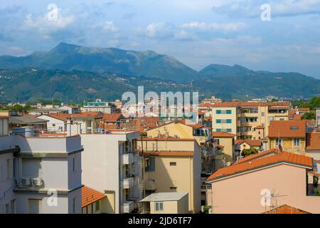 Tetti e residenze di Viareggio con le montagne appenniniche italiane in lontananza. Foto Stock