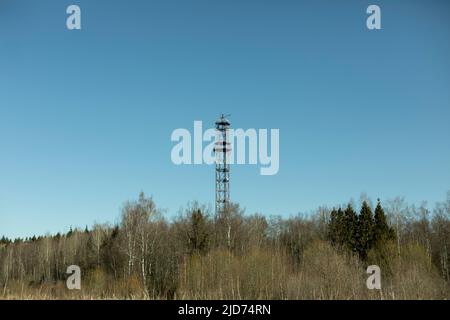 Torre di comunicazione su foresta. Torre TV fuori città. Antenna di alimentazione del segnale. Comunicazione radio ad alta quota. Foto Stock