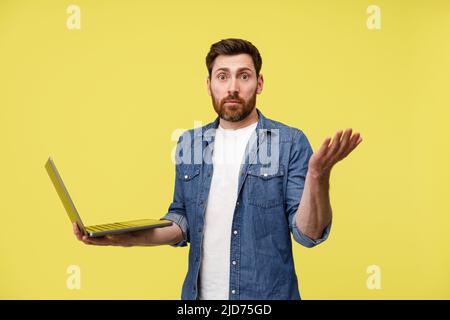 Sorprende l'uomo che tiene un laptop e che diffonde le mani in confusione Foto Stock