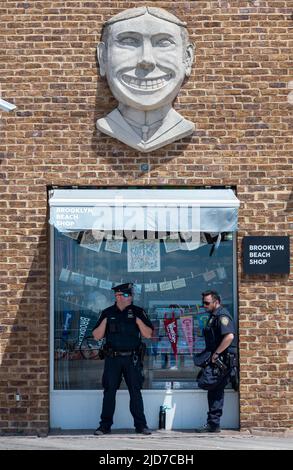 Coney Island, Stati Uniti. 18th giugno 2022. Due funzionari della polizia di New York si prendono una pausa sotto una tenda sotto l'iconico logo di Coney Island. La Coney Island Mermaid Parade è la più grande Art Parade degli Stati Uniti. La sfilata celebra l'inizio dell'estate. I rivelatori vestono come sirene, pesci e altre creature marine. Credit: SOPA Images Limited/Alamy Live News Foto Stock