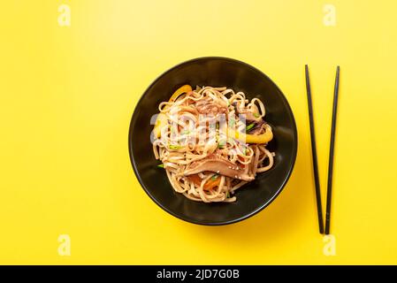 Cibo asiatico. Undon tagliatelle con pollo in un piatto nero Foto Stock