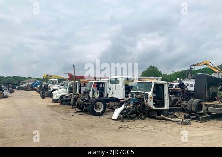 Un sacco di camion abbandonati grandi rotti in un cantiere, camion relitti con parti danneggiate sono in una discarica auto, riciclaggio di automobili dopo gli incidenti Foto Stock