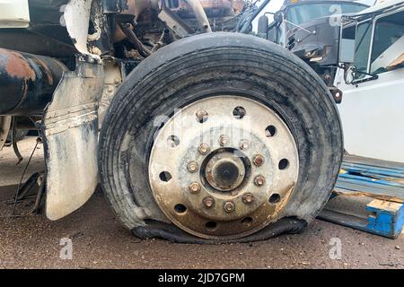 Primo piano della ruota del camion distrutta con uno pneumatico forato o sgonfio in un deposito auto dopo un incidente stradale Foto Stock