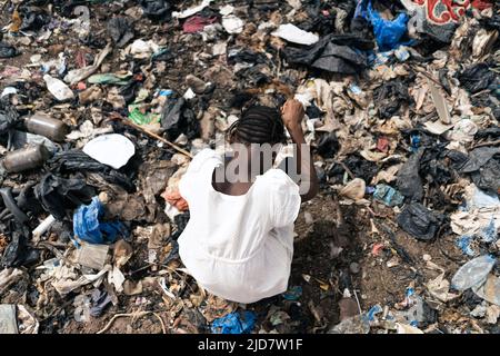 Vista dall'alto di una ragazza africana circondata da rifiuti in cerca di materiale riciclabile Foto Stock