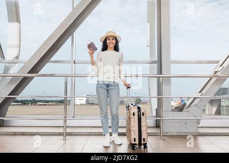 Ritratto di Happy Middle Eastern Female in Straw Hat posa in aeroporto Foto Stock