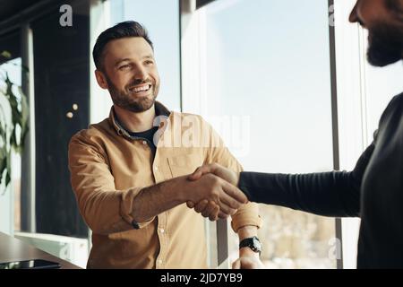 Partnership aziendale. Sorridenti imprenditori maschi che scuotono le mani, celebrando l'accordo di cooperazione in carica Foto Stock