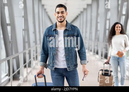 Viaggi aerei. Uomo arabo sorridente con bagagli in posa all'aeroporto Foto Stock