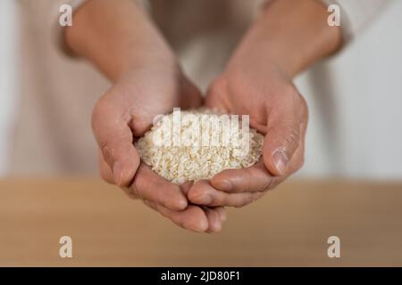 Persona irriconoscibile mani con una manciata di riso Foto Stock