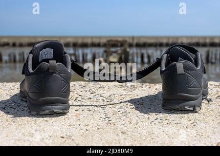 Le scarpe abbandonate al bordo del termine di un percorso demolito con orizzonte marino Foto Stock