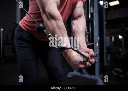 Braccia muscolari con le vene in primo piano, bodybuilder esercizio in cavo crossover palestra macchina Foto Stock