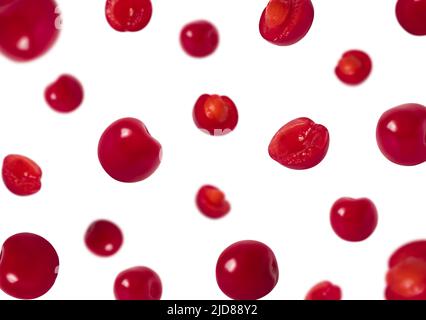 Ciliegie a fette e intere che cadono isolate su sfondo bianco. Ciliegia volante. Modello Berry. Foto Stock