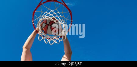vista dall'alto del giocatore di basket getta la palla nel cerchio all'aperto, motivazione. Design poster orizzontale. Intestazione banner Web, spazio di copia. Foto Stock