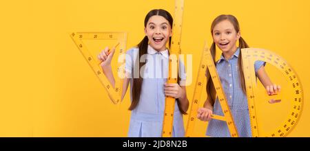 Scuole ragazze amici. È arrivato il ritorno a scuola. Le ragazze felici tengono gli attrezzi geometrici. Torna a scuola. Lezione di geometria. Banner della studentessa scolastica Foto Stock