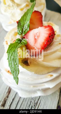 Pavlova meringa torte con panna montata e fragole fresche, foglie di menta. Messa a fuoco selettiva. Spazio di copia. Foto Stock