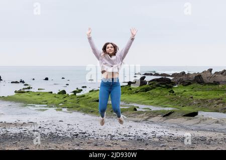 giovane donna che salta sulla spiaggia in primavera Foto Stock