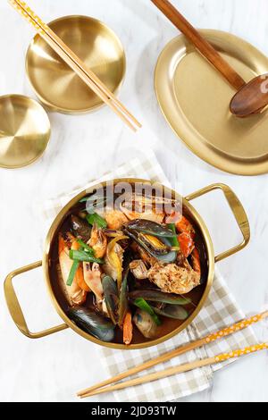 Zuppa coreana Jjampong, mix di pesce piccante Red Noodle, cucina cinese. Vista dall'alto sulla Gold Pan Foto Stock