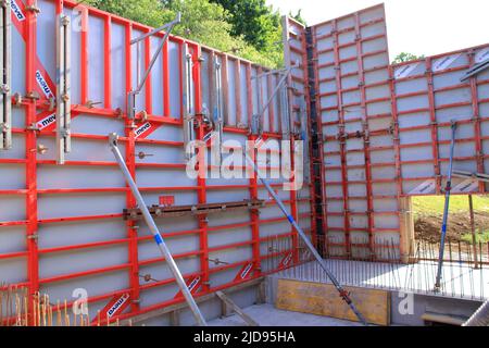 La cassaforma per una parete di calcestruzzo è stata fissata contro lo scivolamento con puntoni Foto Stock