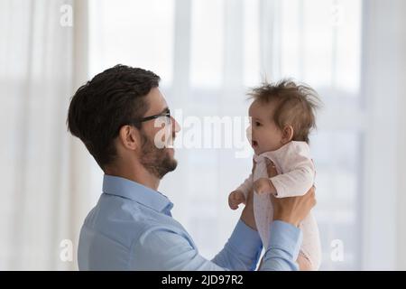 Il giovane papà amorevole tiene gli ascensori sulle mani del suo bambino Foto Stock