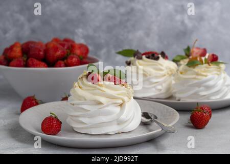 Pavlova meringa torte con panna montata e fragole fresche, foglie di menta. Messa a fuoco selettiva. Spazio di copia. Foto Stock