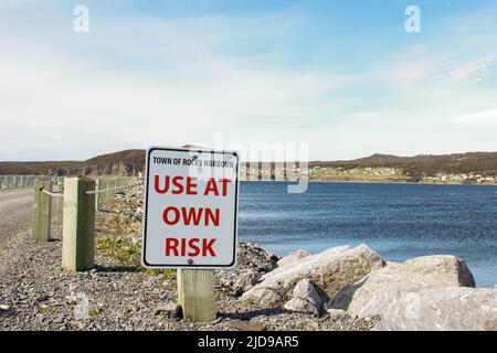 Un cartello che avverte le persone circa l'uso del molo presso il porto roccioso terranova, potrebbe essere pericoloso a causa delle onde Foto Stock