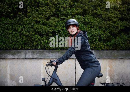 Ritratto di donna d'affari commuter sul modo di lavorare con la bicicletta guardando la macchina fotografica, concetto di stile di vita sostenibile. Foto Stock