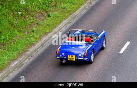 Un'auto sportiva blu convertibile MG 1973-74 con tetto in giù è in moto lungo la strada a doppia carreggiata a Dundee, Scozia Foto Stock