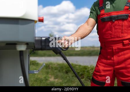 Lavoratore senior in piedi sulla stazione di servizio e auto di rifornimento. Foto Stock