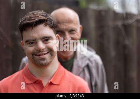 Ritratto di padre felice con suo figlio giovane con sindrome di Down all'aperto. Foto Stock